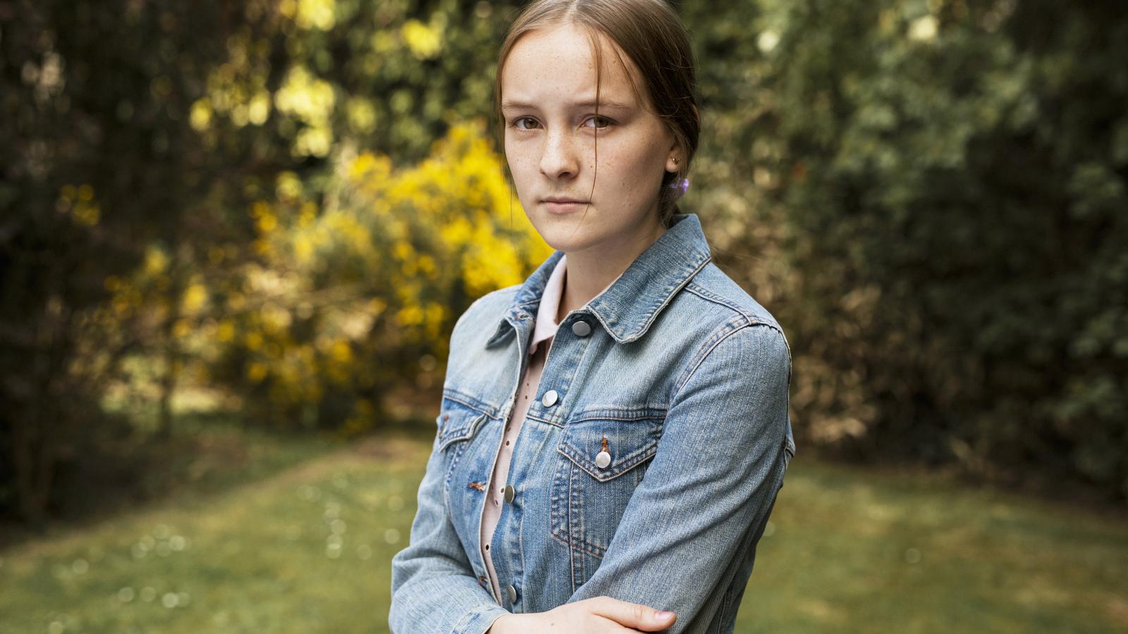Young girl in denim jacket standing in garden