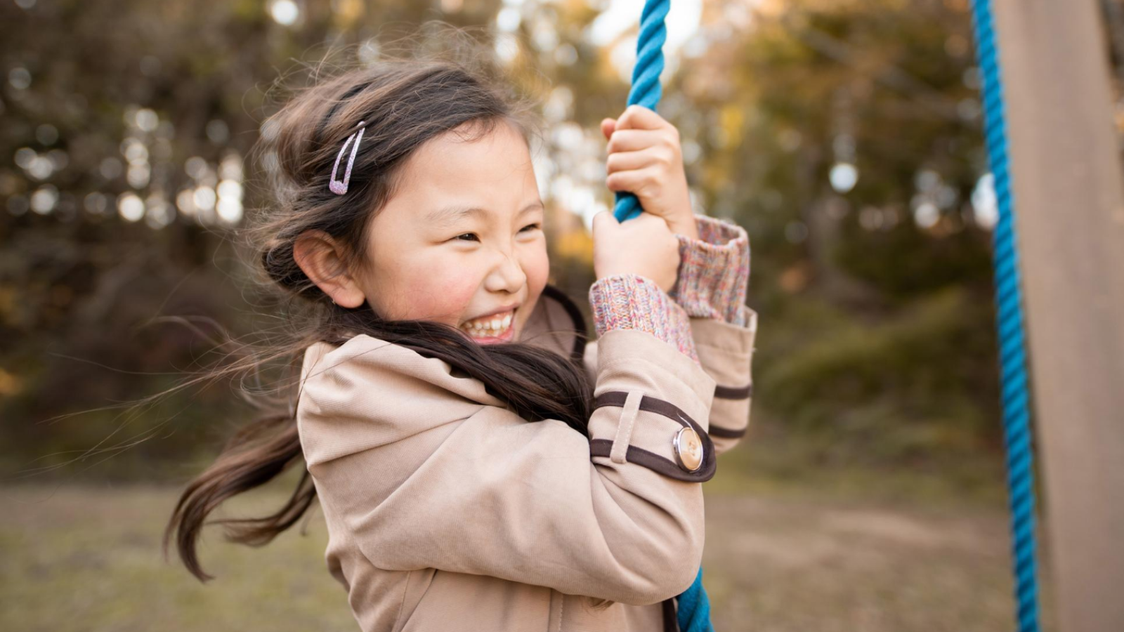 Smiling girl playing on a swing 