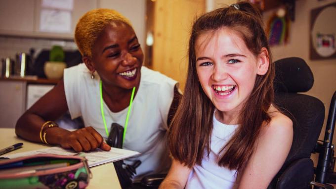 A girl laughing next to a smiling Barnardo's worker