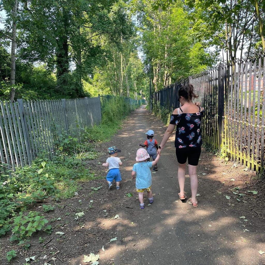 An adult and three children walk along a path