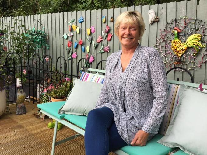 A foster carer sitting in her garden smiling