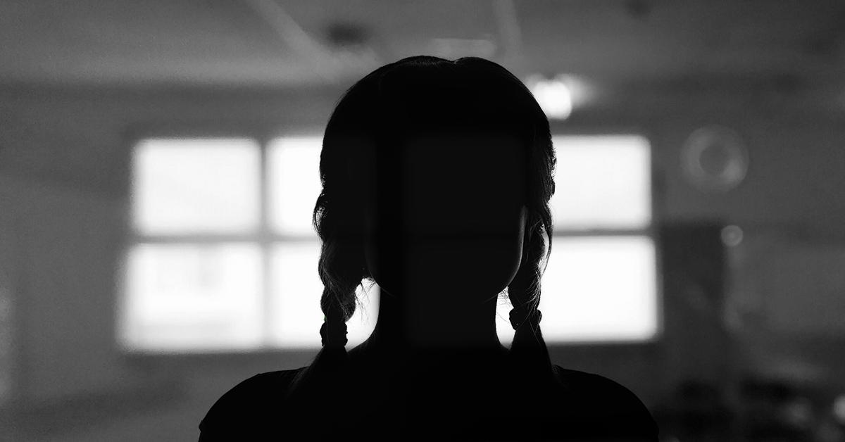 Silhouette of young girl with plaits in front of a window