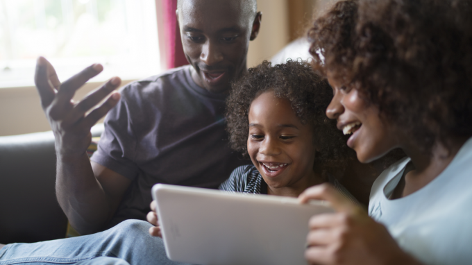 Young family sitting and laughing looking at an ipad